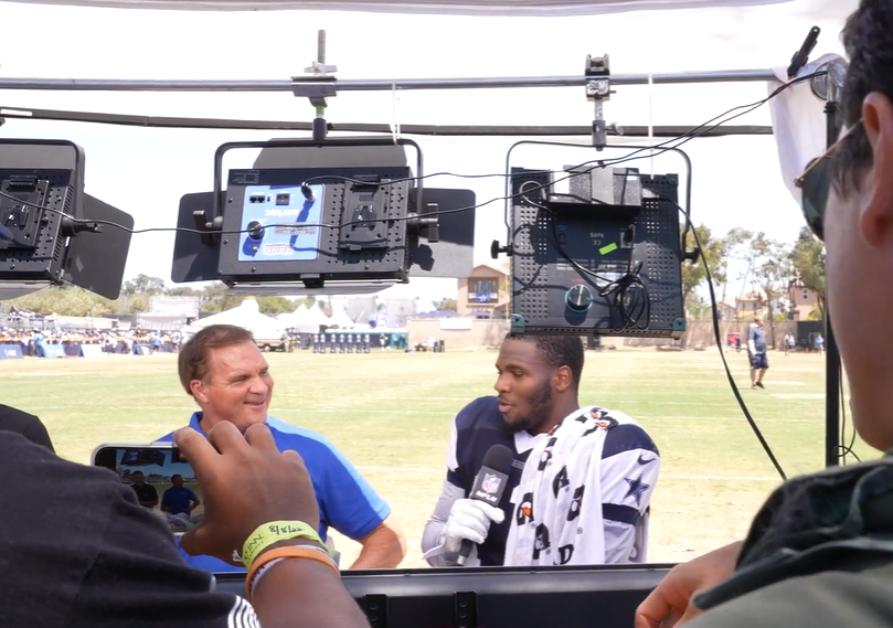 a sports caster interviewing Dallas Cowboy football player in uniform at the Oxnard Training Camp