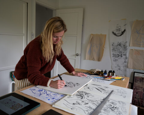 Artist Atelier Clara Mari at her drafting table working on a series of sketches in her studio