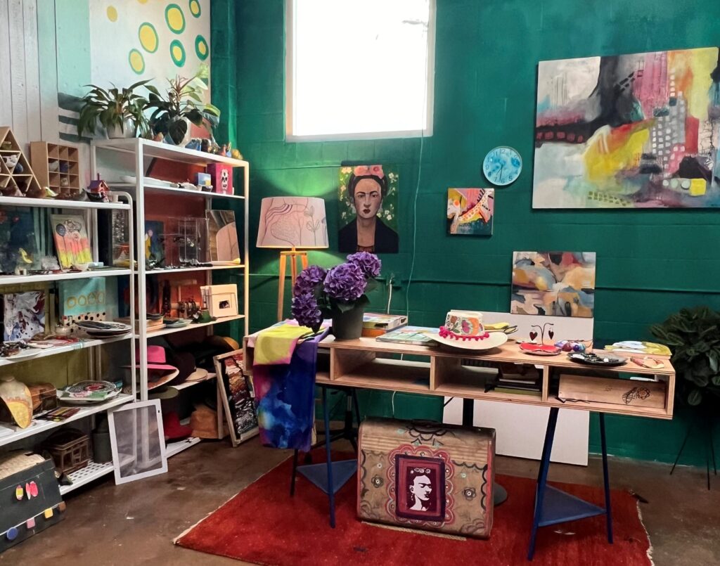 An Artist Studio with a sea green wall a frida painting, desk, and various art creations